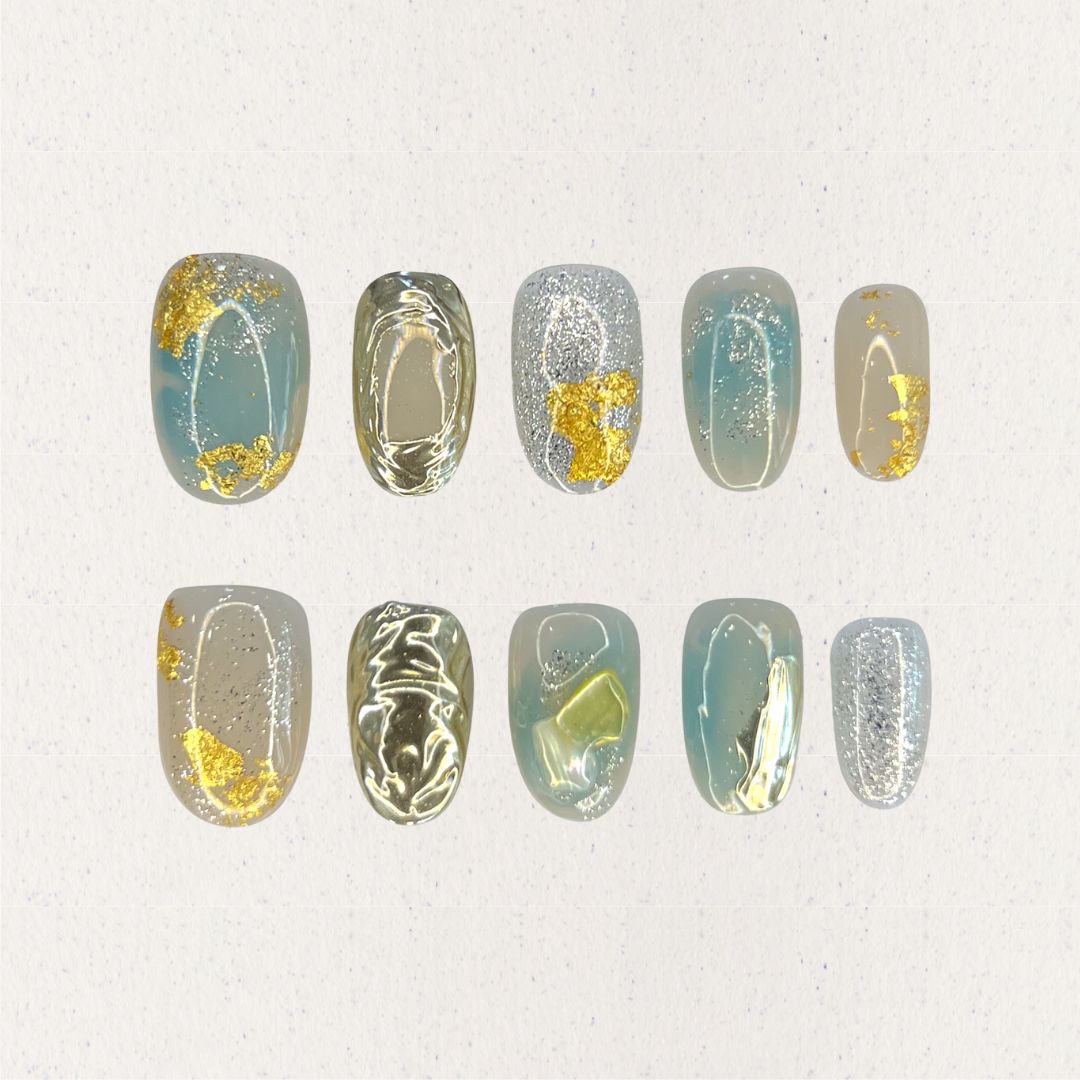 Golden Veil nail set features gold foil highlights on pastel blue and gray bases, adding an elegant shimmer and refined depth to each nail.