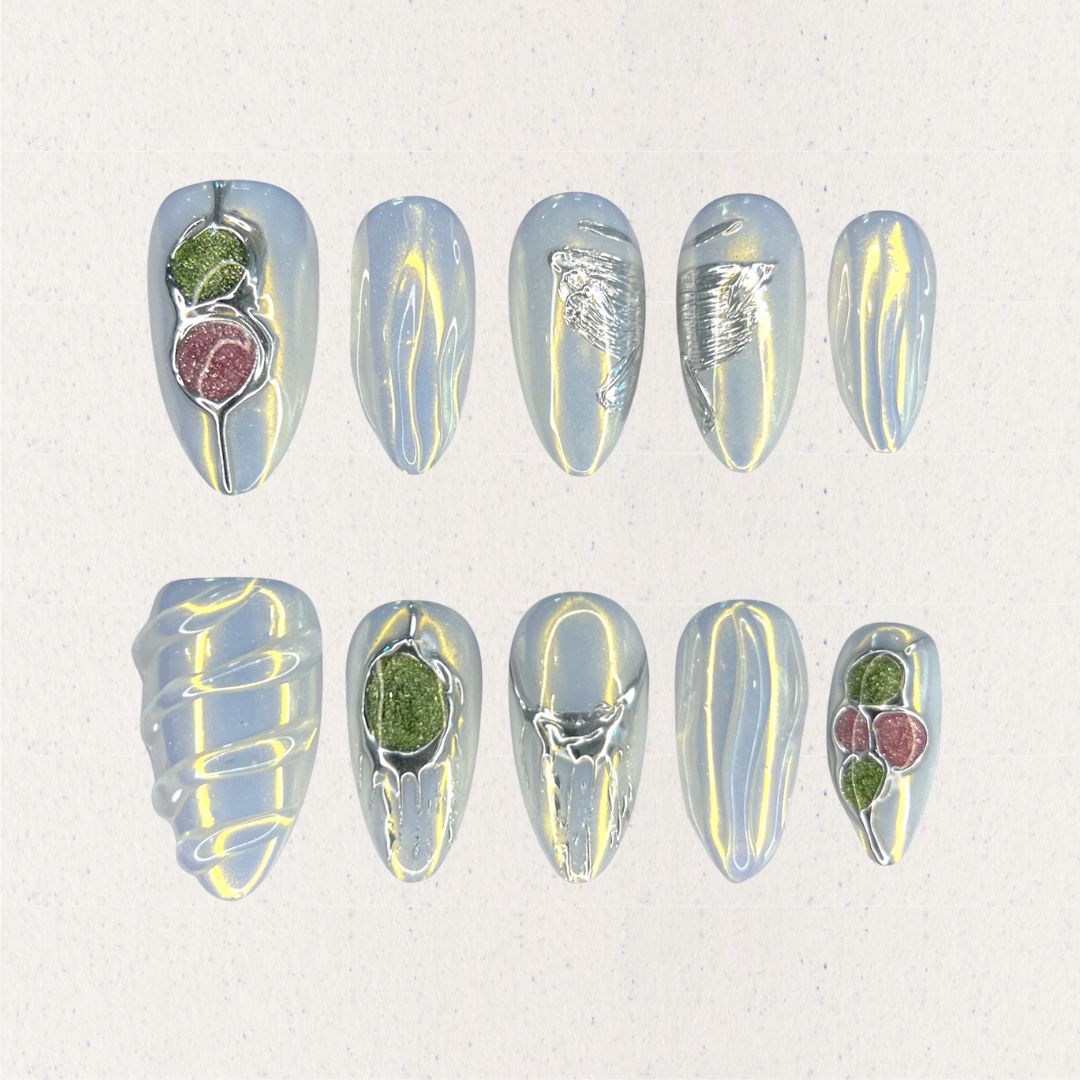 Dewy Berries nail set draws inspiration from dew-kissed berries in a misty meadow. With shimmering blue tones and 3D green and red accents resembling luscious berries, this design celebrates the charm of nature at dawn.