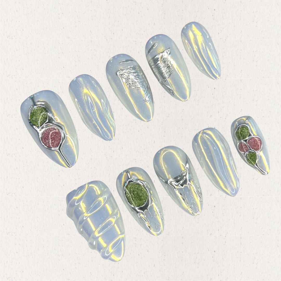 Dewy Berries nail set draws inspiration from dew-kissed berries in a misty meadow. With shimmering blue tones and 3D green and red accents resembling luscious berries, this design celebrates the charm of nature at dawn.