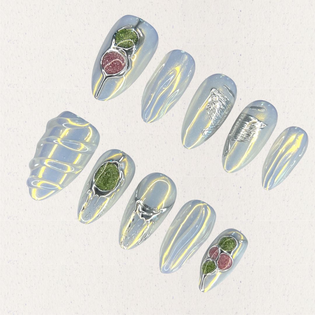 Dewy Berries nail set draws inspiration from dew-kissed berries in a misty meadow. With shimmering blue tones and 3D green and red accents resembling luscious berries, this design celebrates the charm of nature at dawn.