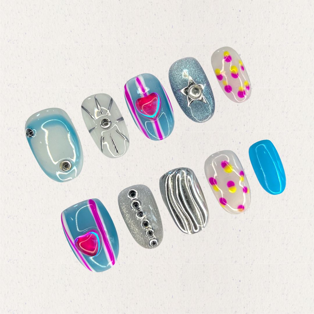 Cosmic Heartbeat nail set combines silver and blue metallic bases with neon pink hearts, sharp star shapes, and polka dot details. This design channels a lively, otherworldly rhythm inspired by cosmic waves and pulsars.