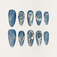 This press-on nail set, titled "Metallic Tide," showcases a deep ocean blue base with delicate marbled textures, resembling swirling water patterns. The standout silver metallic accents create fluid, wave-like designs that mimic flowing liquid metal. The overall aesthetic is modern, minimalist, and artistic, blending nature's elegance with a futuristic touch.