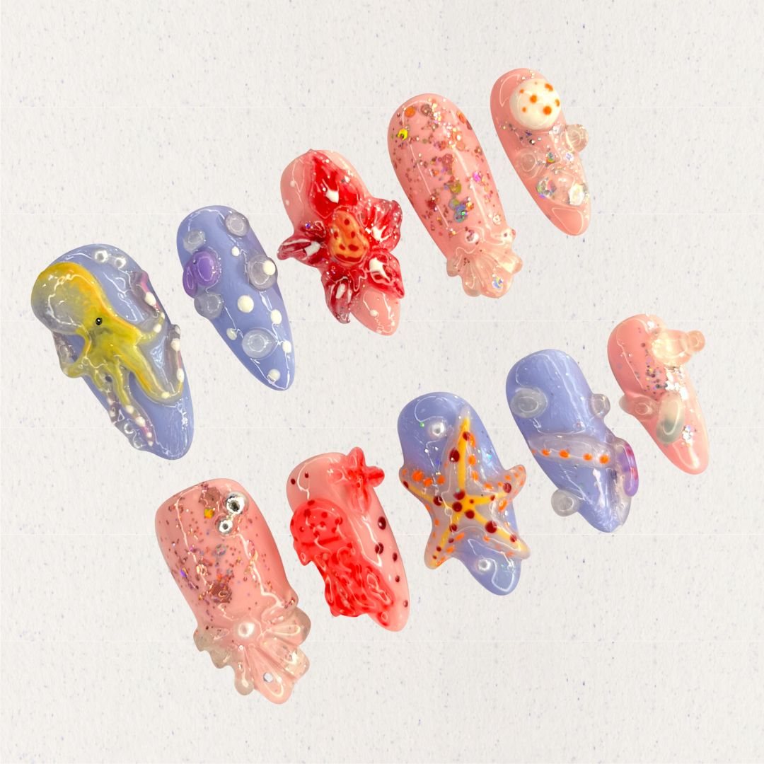 Ocean Realm nail set features vibrant sea-inspired designs, including octopuses, starfish, and jellyfish in vivid reds, blues, and purples. Enhanced with glitter and 3D details, this set celebrates the wonder of marine ecosystems.