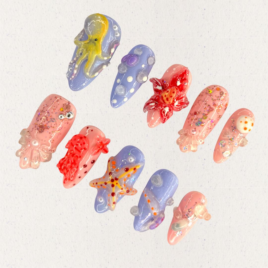 Ocean Realm nail set features vibrant sea-inspired designs, including octopuses, starfish, and jellyfish in vivid reds, blues, and purples. Enhanced with glitter and 3D details, this set celebrates the wonder of marine ecosystems.