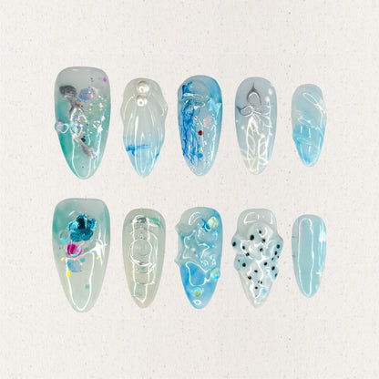 This press-on nail set, titled "Aqua Serenity," features soothing aqua blue hues paired with translucent textures, pearl embellishments, and abstract ocean-inspired patterns. Each design mimics the gentle flow of water, with artistic splashes of color, subtle waves, and delicate details that bring a serene and contemporary oceanic vibe to life.