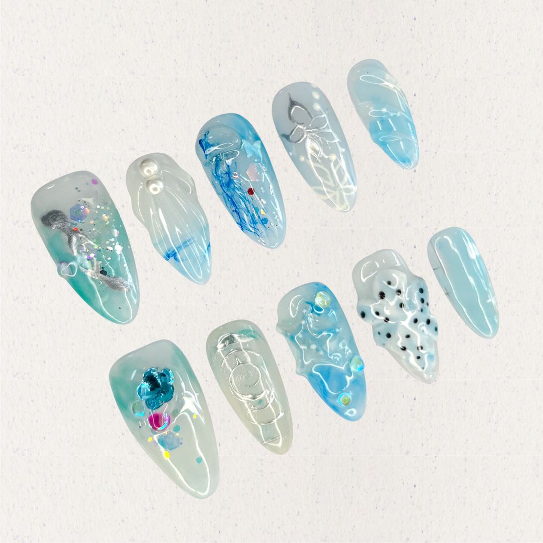 This press-on nail set, titled "Aqua Serenity," features soothing aqua blue hues paired with translucent textures, pearl embellishments, and abstract ocean-inspired patterns. Each design mimics the gentle flow of water, with artistic splashes of color, subtle waves, and delicate details that bring a serene and contemporary oceanic vibe to life.