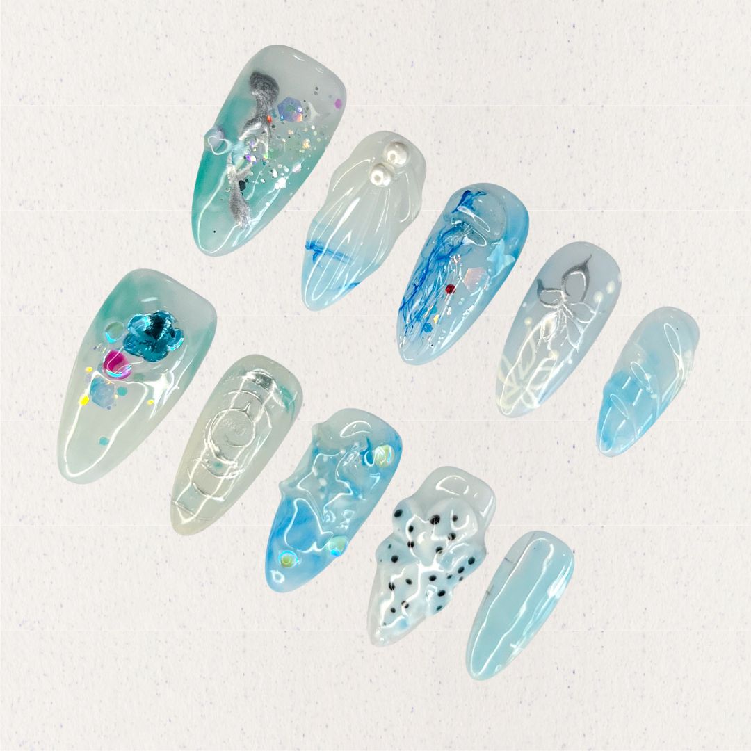 This press-on nail set, titled "Aqua Serenity," features soothing aqua blue hues paired with translucent textures, pearl embellishments, and abstract ocean-inspired patterns. Each design mimics the gentle flow of water, with artistic splashes of color, subtle waves, and delicate details that bring a serene and contemporary oceanic vibe to life.