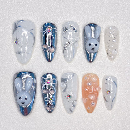 Moonlit Bunny nail set highlights 3D bunny motifs, silver tones, and pearl accents, creating a whimsical yet elegant design under a moonlit glow.