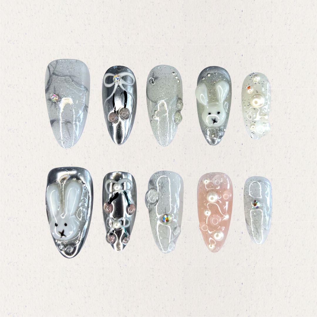 Moonlit Bunny nail set highlights 3D bunny motifs, silver tones, and pearl accents, creating a whimsical yet elegant design under a moonlit glow.