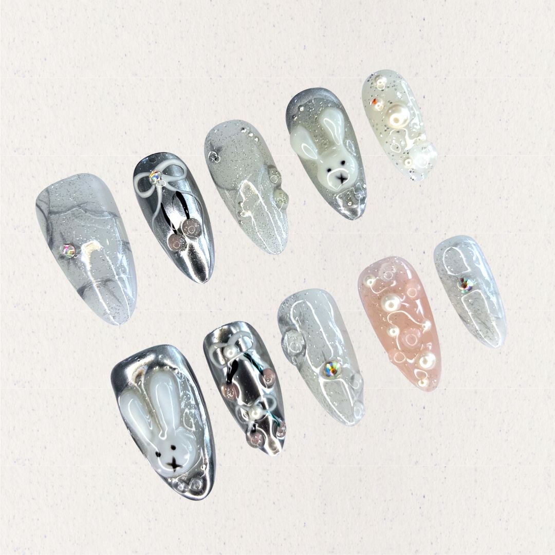 Moonlit Bunny nail set highlights 3D bunny motifs, silver tones, and pearl accents, creating a whimsical yet elegant design under a moonlit glow.