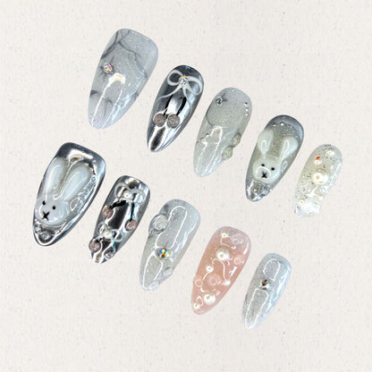 Moonlit Bunny nail set highlights 3D bunny motifs, silver tones, and pearl accents, creating a whimsical yet elegant design under a moonlit glow.