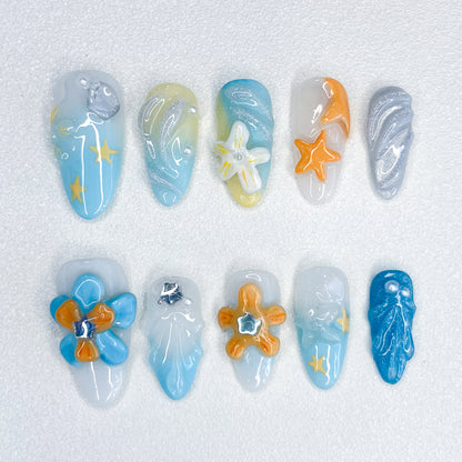 A stunning press-on nail set with intricate designs inspired by the ocean and floral elements. The vibrant colors and floral accents give it a fresh, tropical look, perfect for beachy vibes or any outfit that calls for a touch of nature.