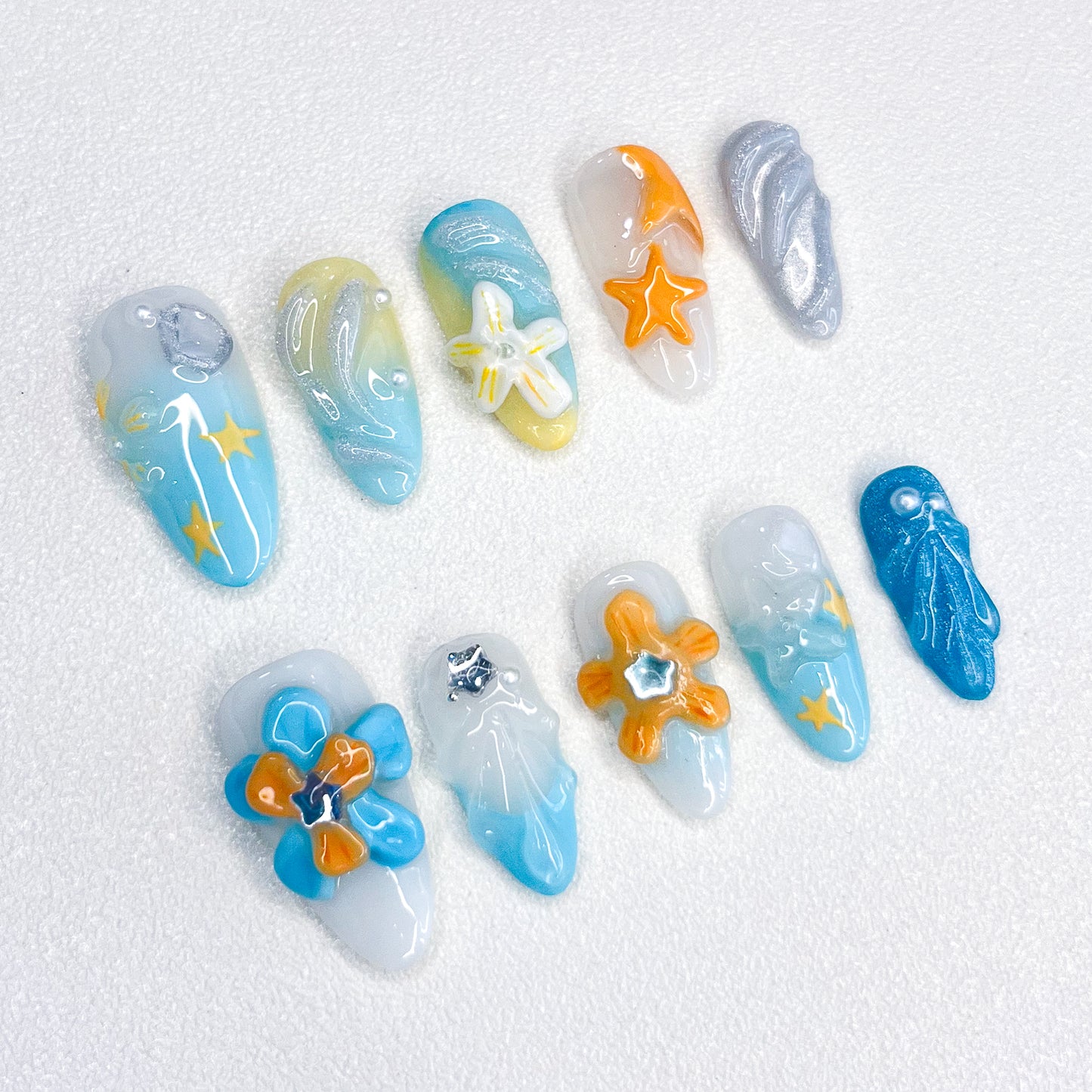 A stunning press-on nail set with intricate designs inspired by the ocean and floral elements. The vibrant colors and floral accents give it a fresh, tropical look, perfect for beachy vibes or any outfit that calls for a touch of nature.