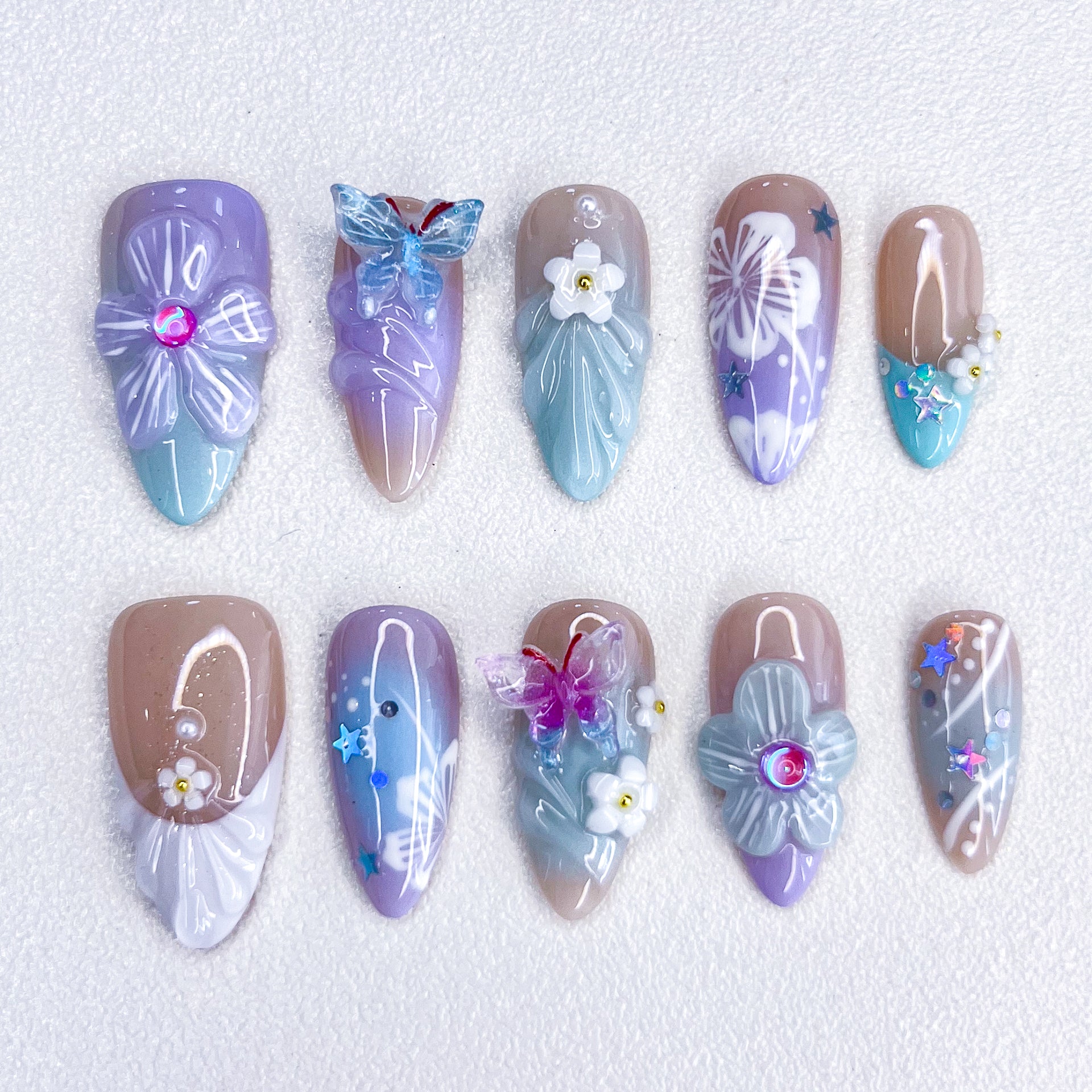 A delicate set of press-on nails featuring seashell and floral designs, blending ocean charm with floral elegance for a serene, coastal-inspired style.