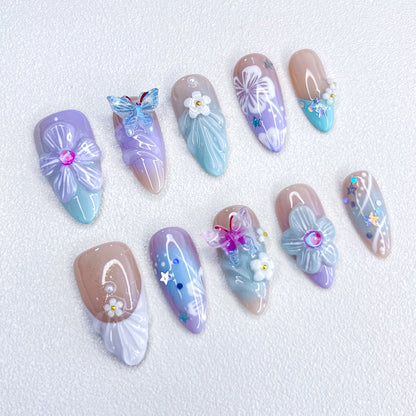 A delicate set of press-on nails featuring seashell and floral designs, blending ocean charm with floral elegance for a serene, coastal-inspired style.