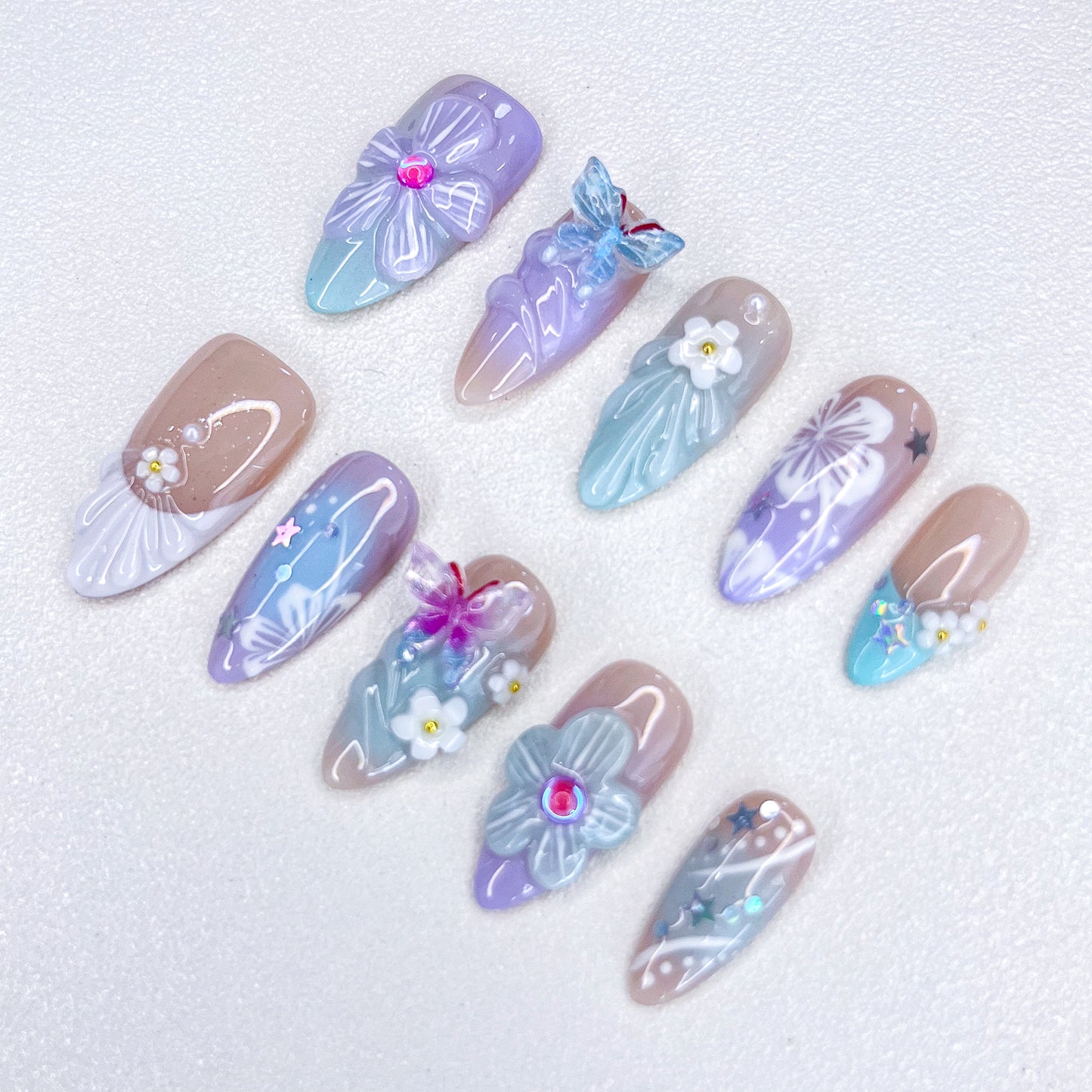 A delicate set of press-on nails featuring seashell and floral designs, blending ocean charm with floral elegance for a serene, coastal-inspired style.