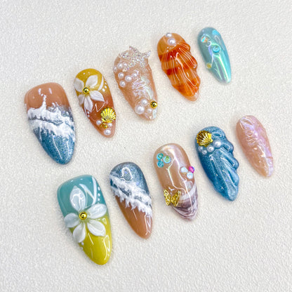 A lively set of press-on nails adorned with multicolored seashells, pearls, and wave motifs, evoking the beauty and mystery of a coral reef.