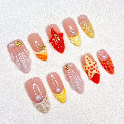 A delicate press-on nail set with a pink base, adorned with seashells, starfish, and pearl details, creating a serene, beach-inspired style that’s both elegant and refreshing.