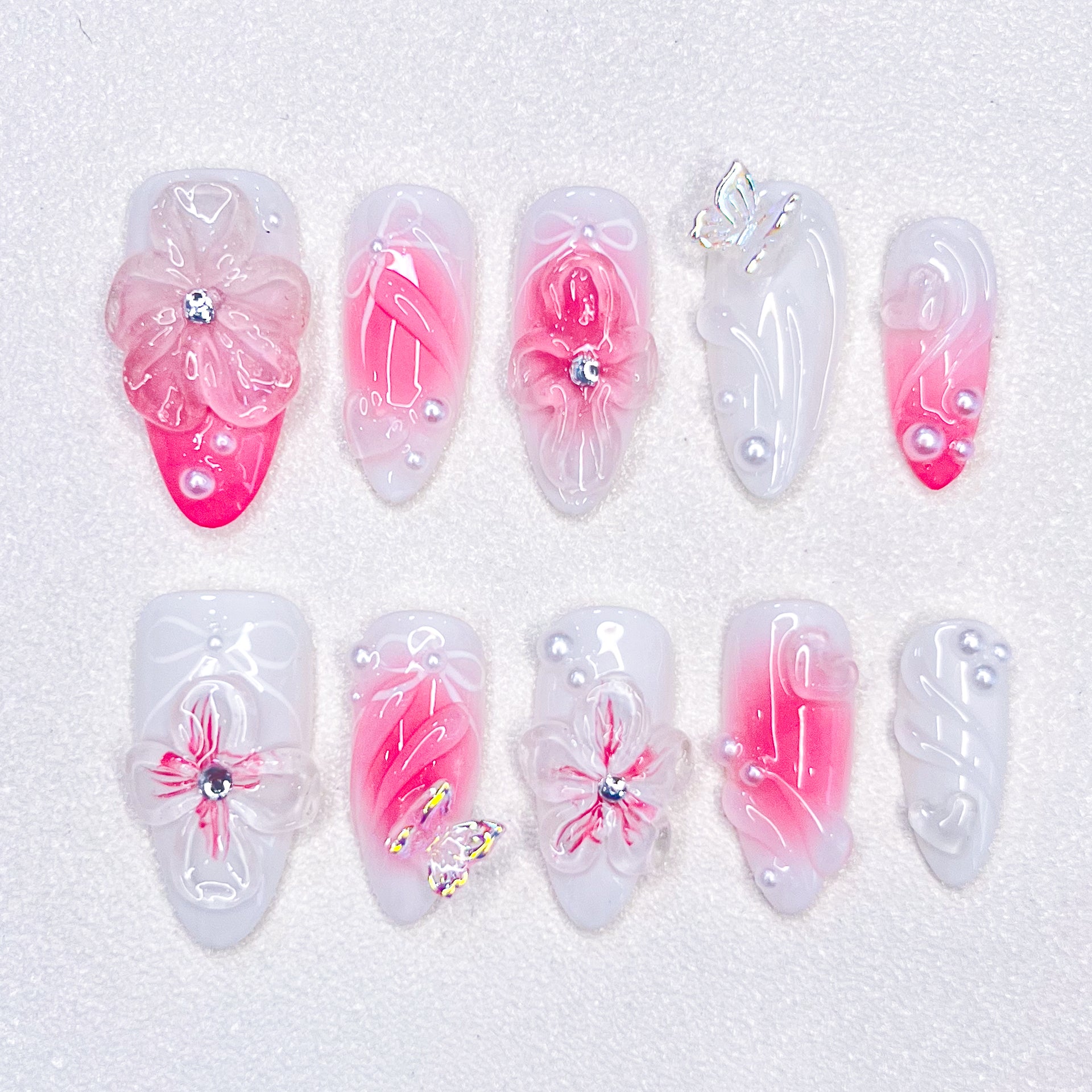 A delicate press-on nail set with a pink and white base, adorned with wave patterns and floral details, creating a harmonious blend of ocean and blossom for a soft, elegant style.