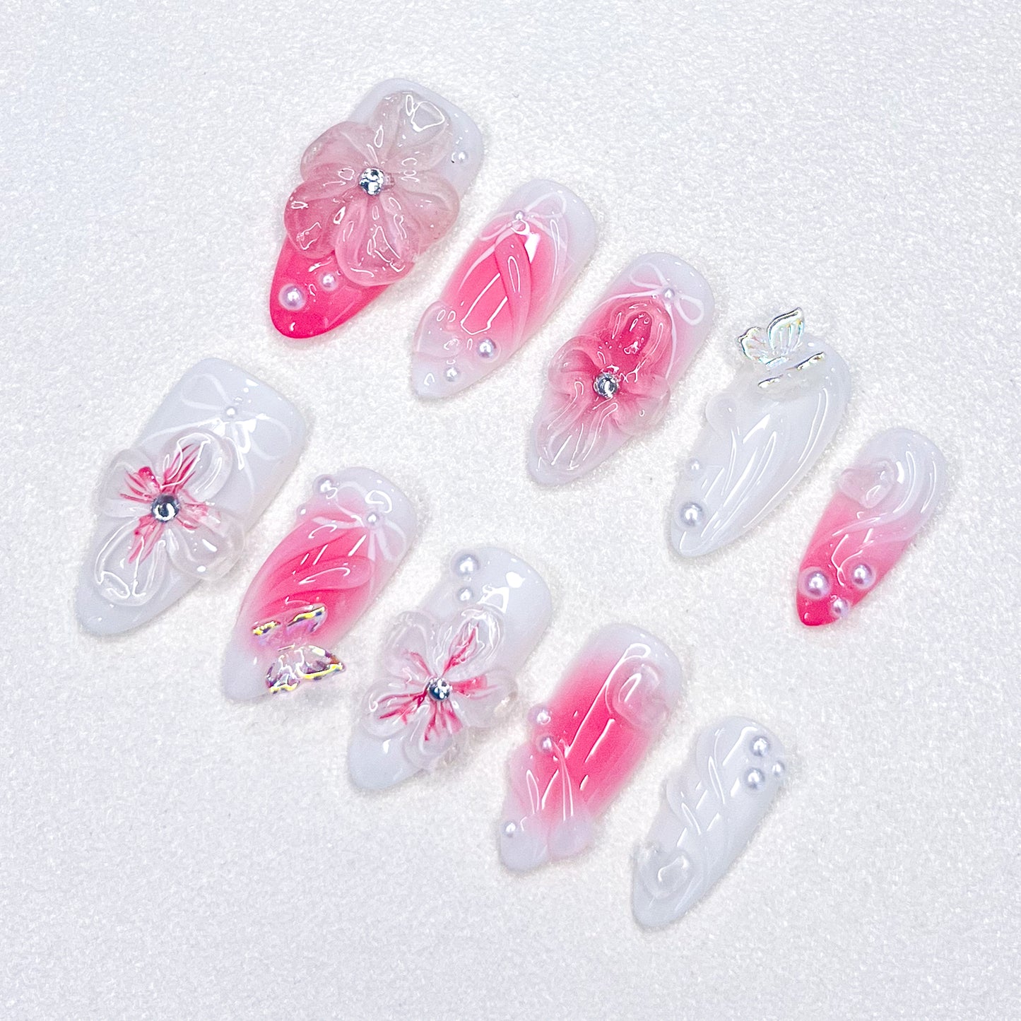 A delicate press-on nail set with a pink and white base, adorned with wave patterns and floral details, creating a harmonious blend of ocean and blossom for a soft, elegant style.