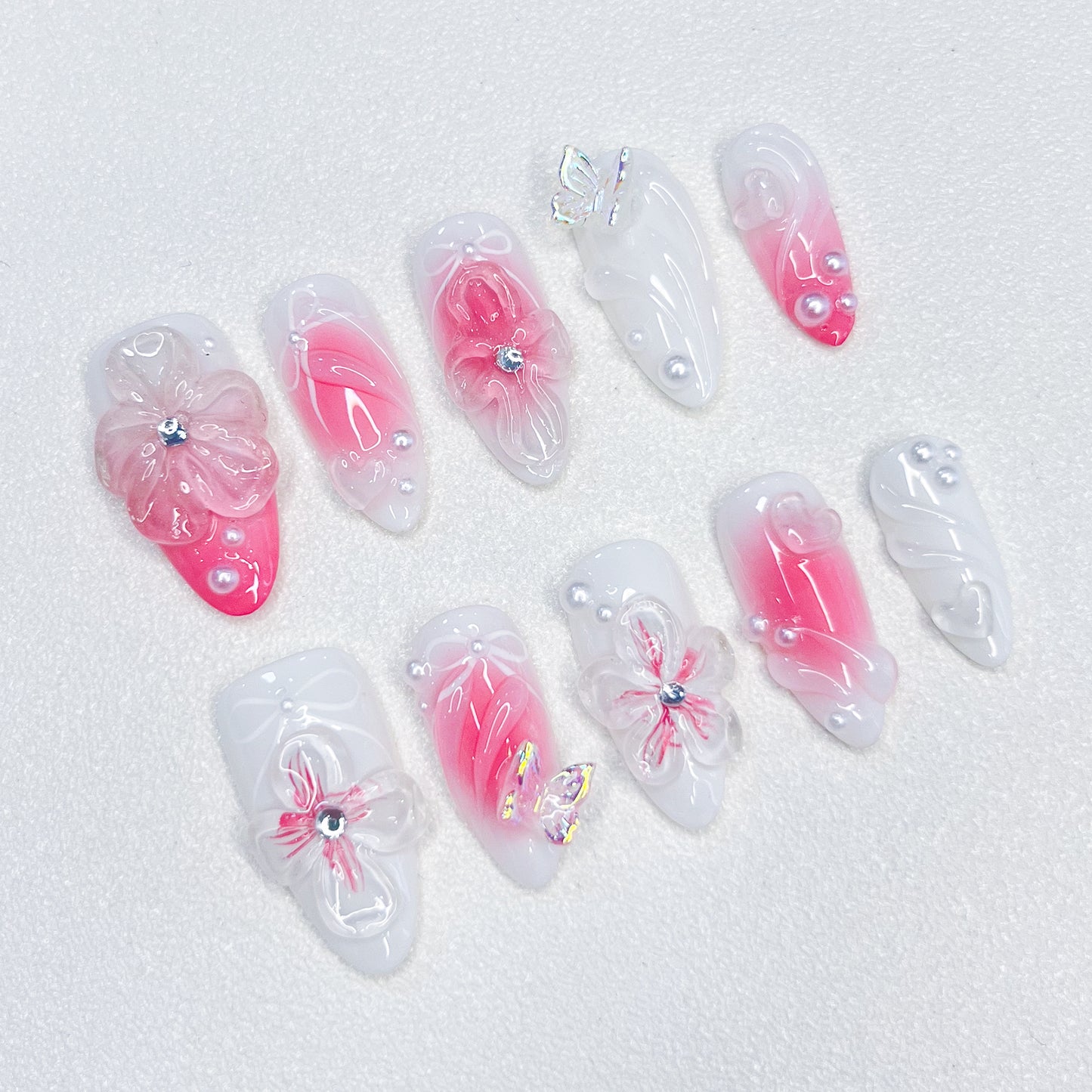 A delicate press-on nail set with a pink and white base, adorned with wave patterns and floral details, creating a harmonious blend of ocean and blossom for a soft, elegant style.