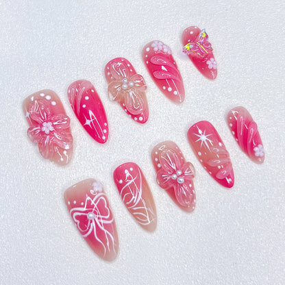 Sakura Elegance 3D pink press-on nails featuring cherry blossoms, butterflies, bows, and pearl details, creating a delicate and romantic style ideal for elegant occasions.