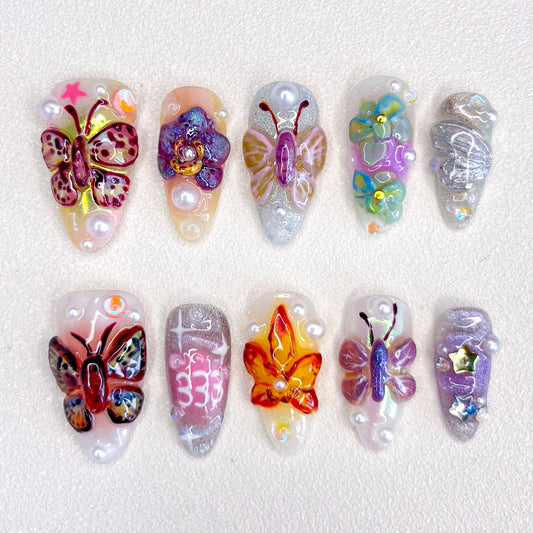 3D nail art featuring vibrant butterflies and flowers with pearl accents on a shimmering base.