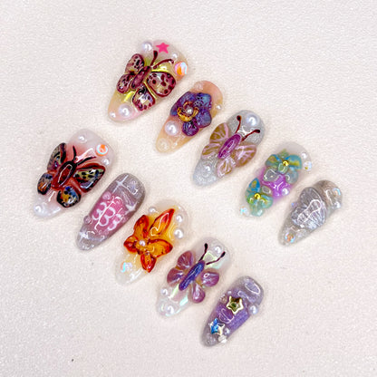 3D nail art featuring vibrant butterflies and flowers with pearl accents on a shimmering base.