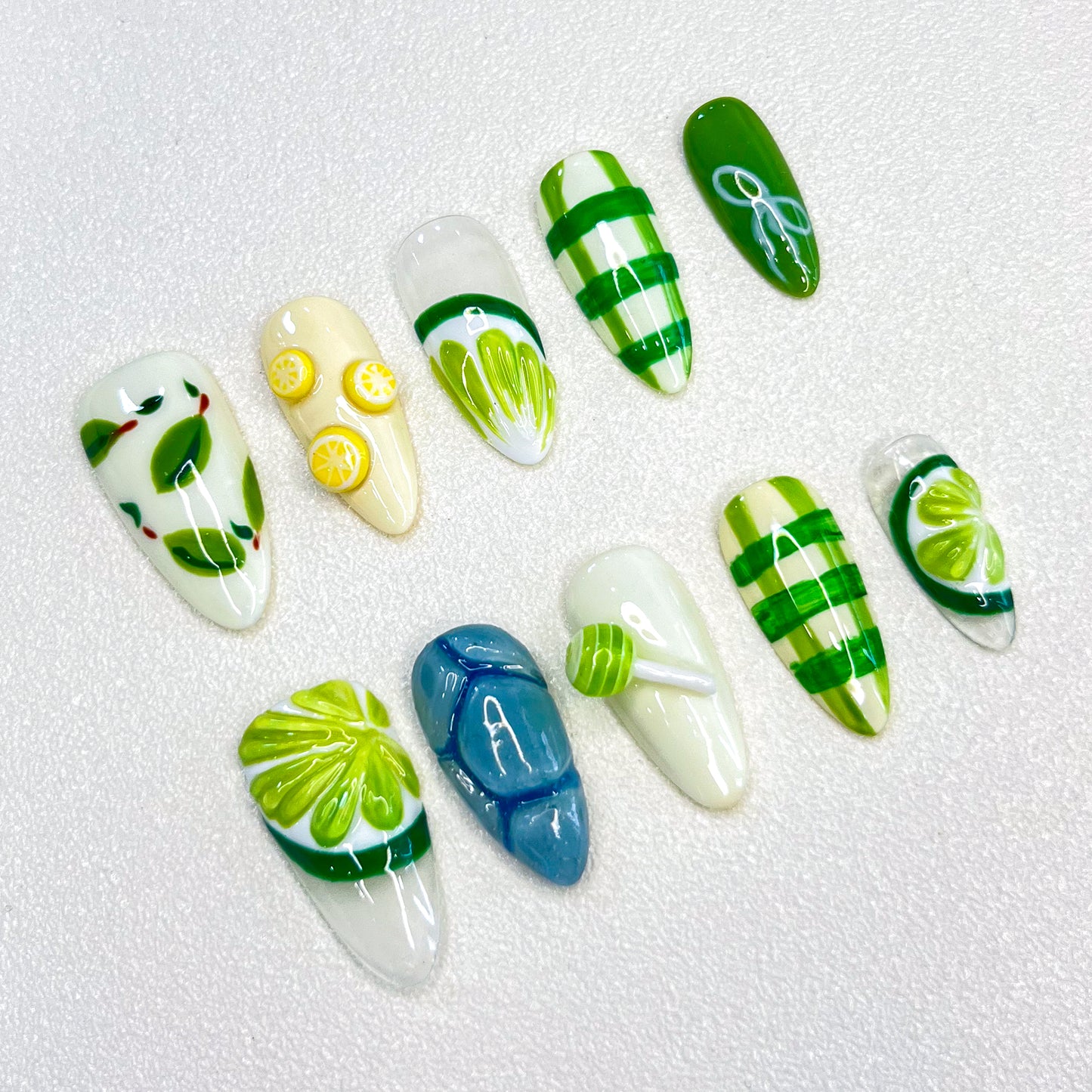 3D nail design featuring green leaves, lemons, and refreshing patterns in shades of green and yellow.