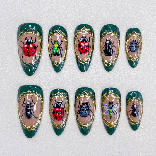 Beetle Bloom press-on nails with hand-painted beetles and golden frames, designed for a unique and bold fashion statement.