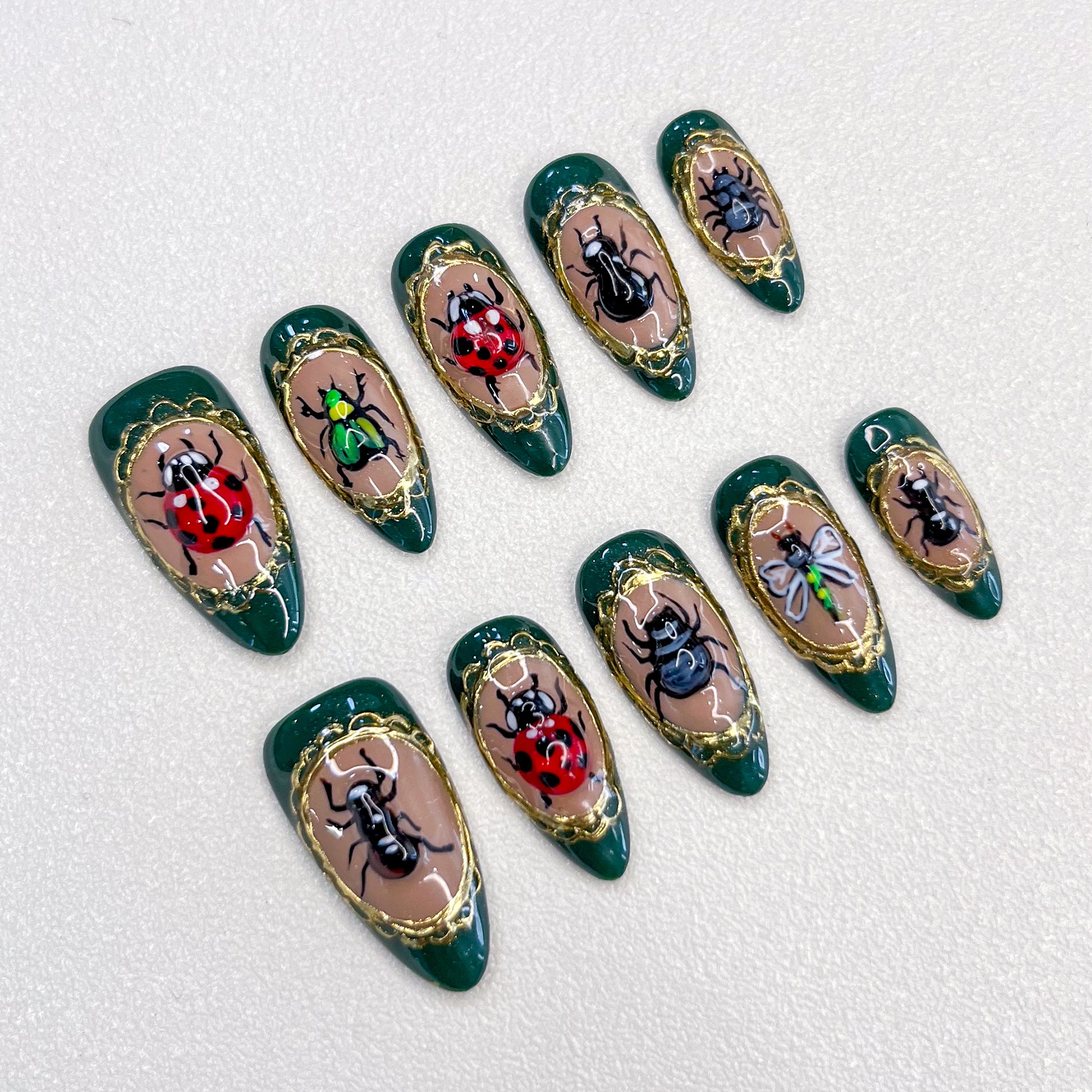 Beetle Bloom press-on nails with hand-painted beetles and golden frames, designed for a unique and bold fashion statement.