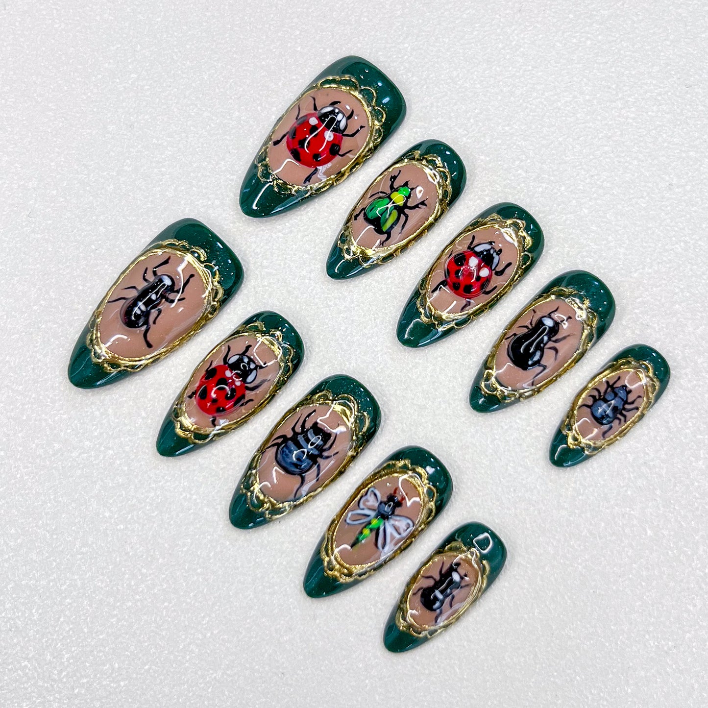 Beetle Bloom press-on nails with hand-painted beetles and golden frames, designed for a unique and bold fashion statement.