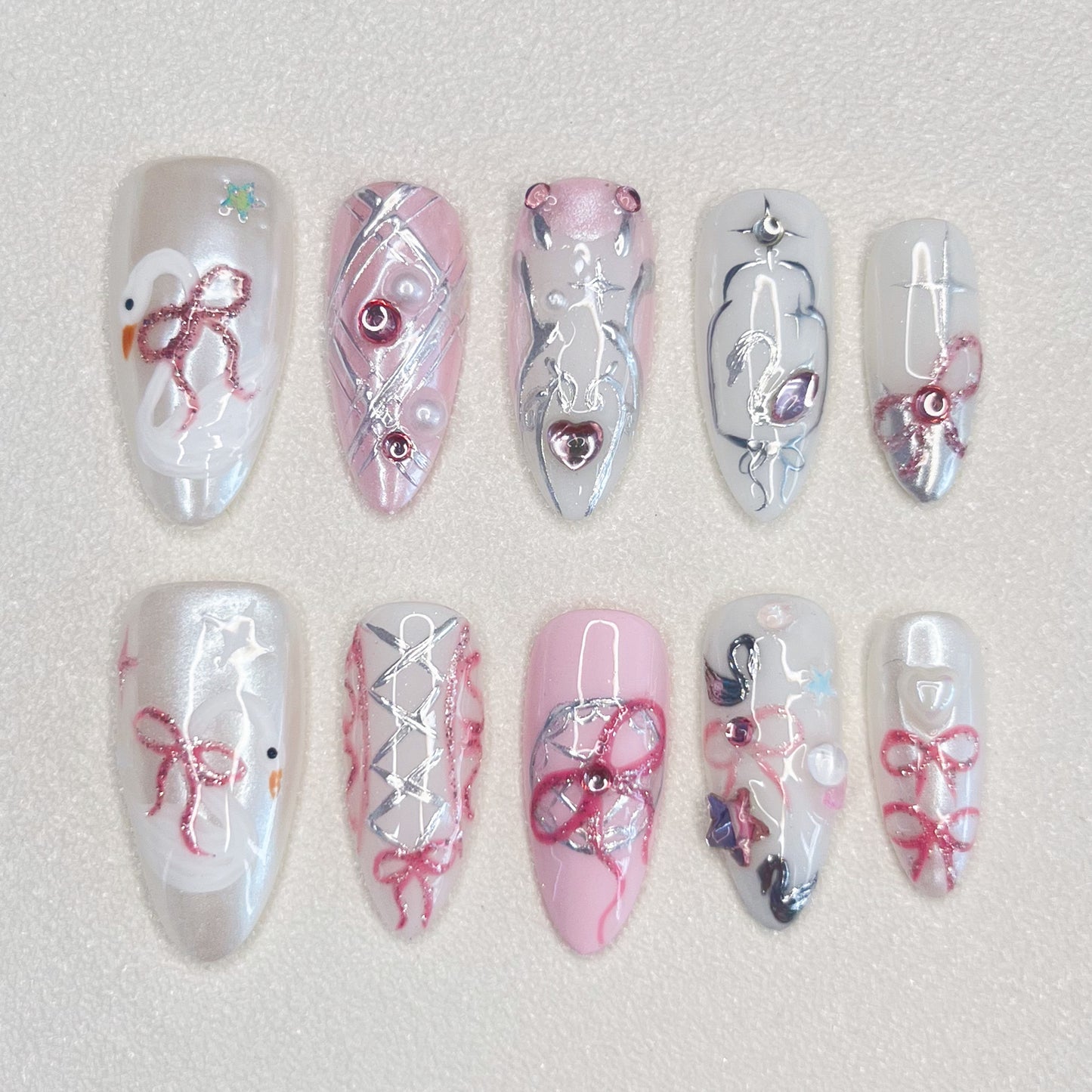 Ribbon Reverie press-on nails with pink tones, lace patterns, and ribbon accents, ideal for a soft, romantic appearance.