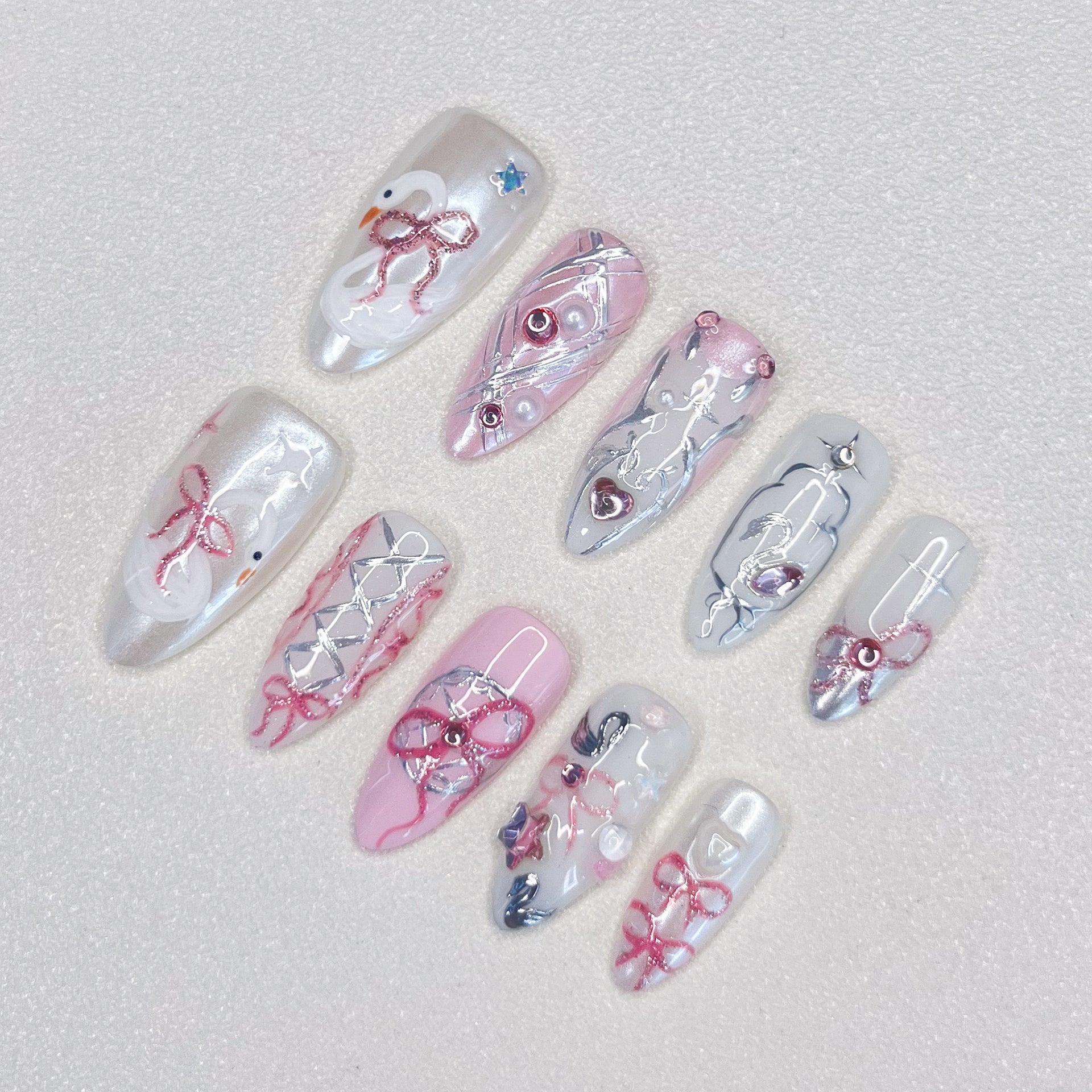 Ribbon Reverie press-on nails with pink tones, lace patterns, and ribbon accents, ideal for a soft, romantic appearance.