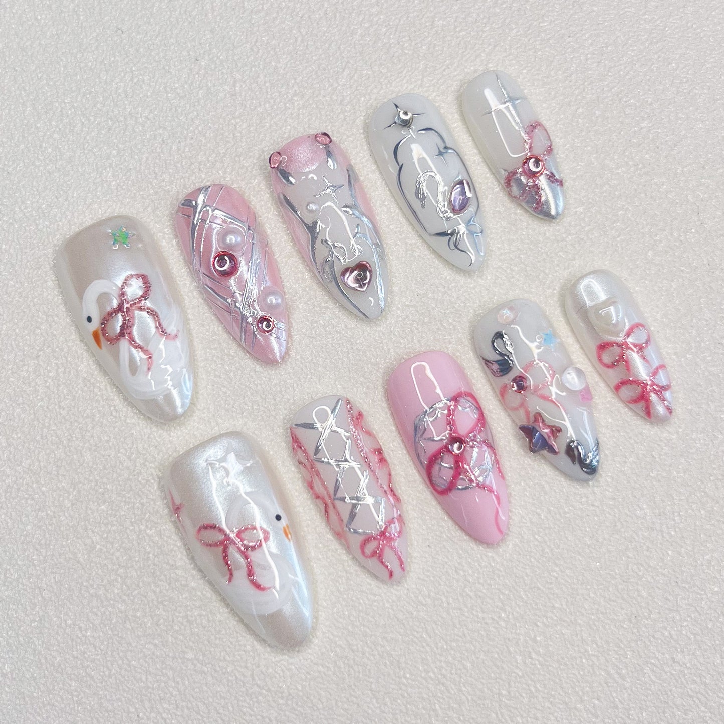 Ribbon Reverie press-on nails with pink tones, lace patterns, and ribbon accents, ideal for a soft, romantic appearance.