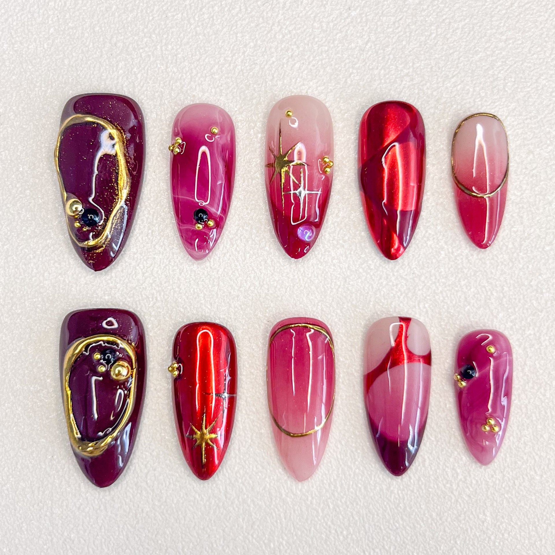 Scarlet Twilight press-on nails with rich red tones, golden accents, and marbled patterns for a luxurious, refined style.