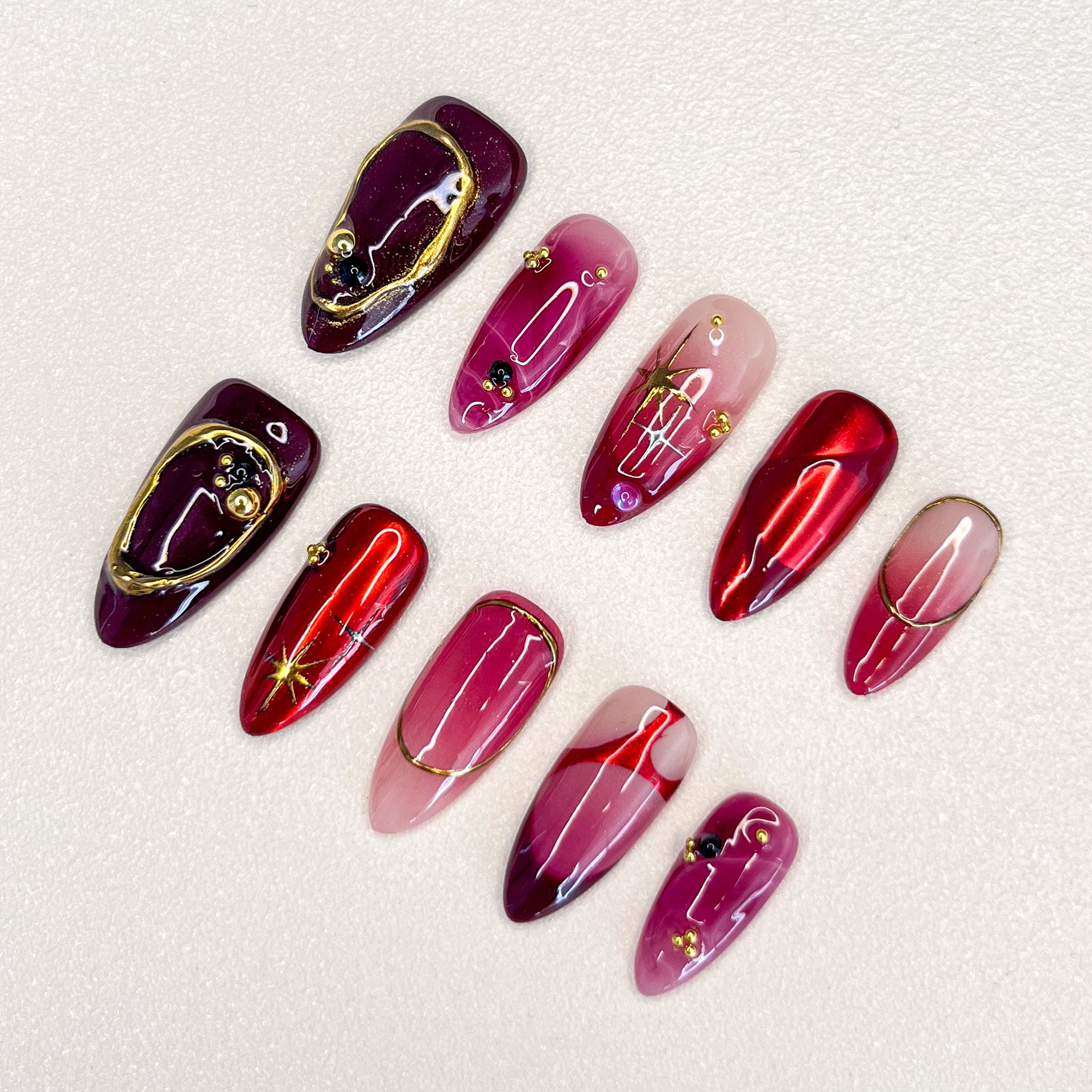 Scarlet Twilight press-on nails with rich red tones, golden accents, and marbled patterns for a luxurious, refined style.