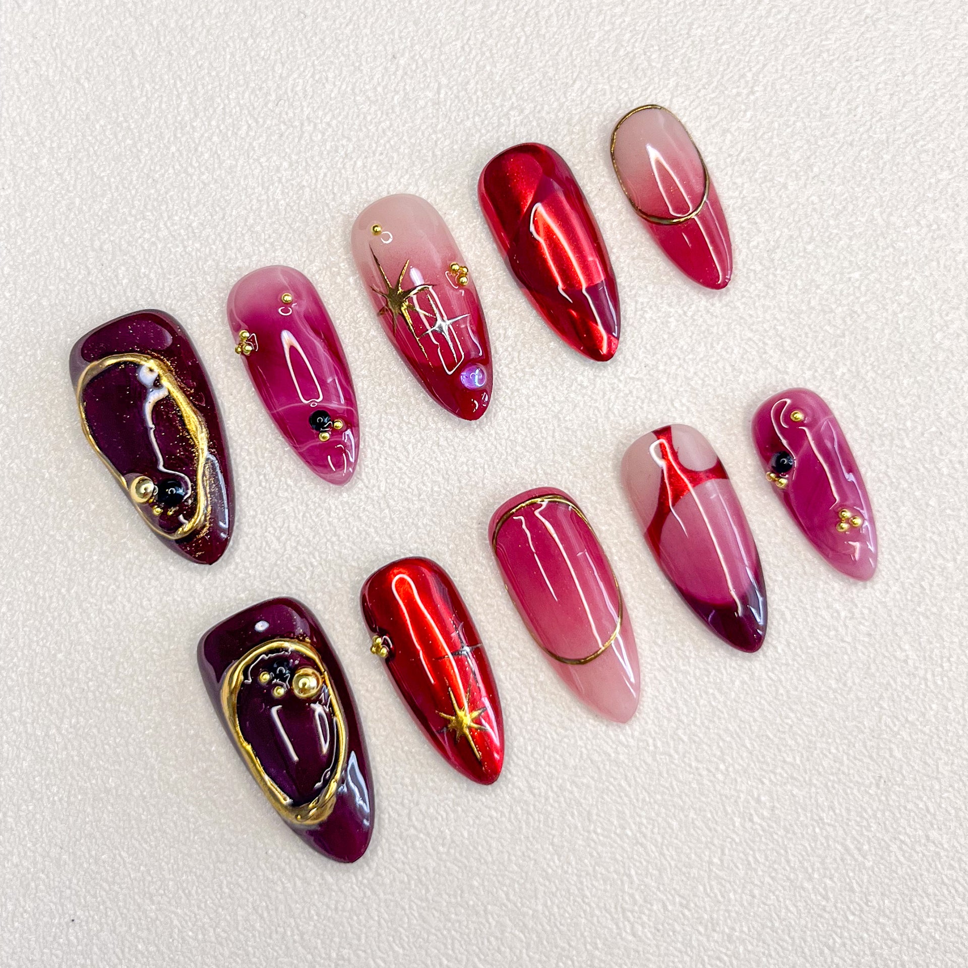 Scarlet Twilight press-on nails with rich red tones, golden accents, and marbled patterns for a luxurious, refined style.