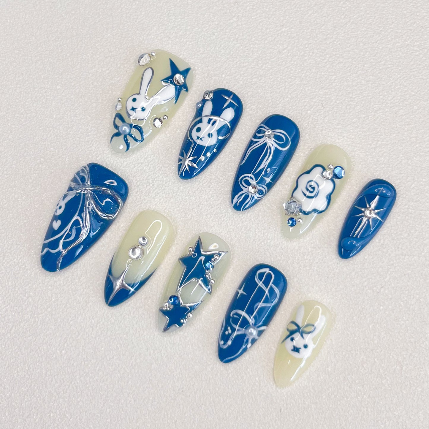 Lunar Bunny press-on nails with cute rabbit designs, star accents, and elegant ribbon details in blue and white tones.