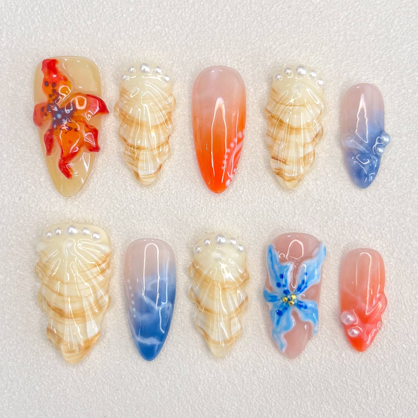 Sunset Coral press-on nails with coral accents, shells, and ocean hues for a beach-inspired, vibrant style.