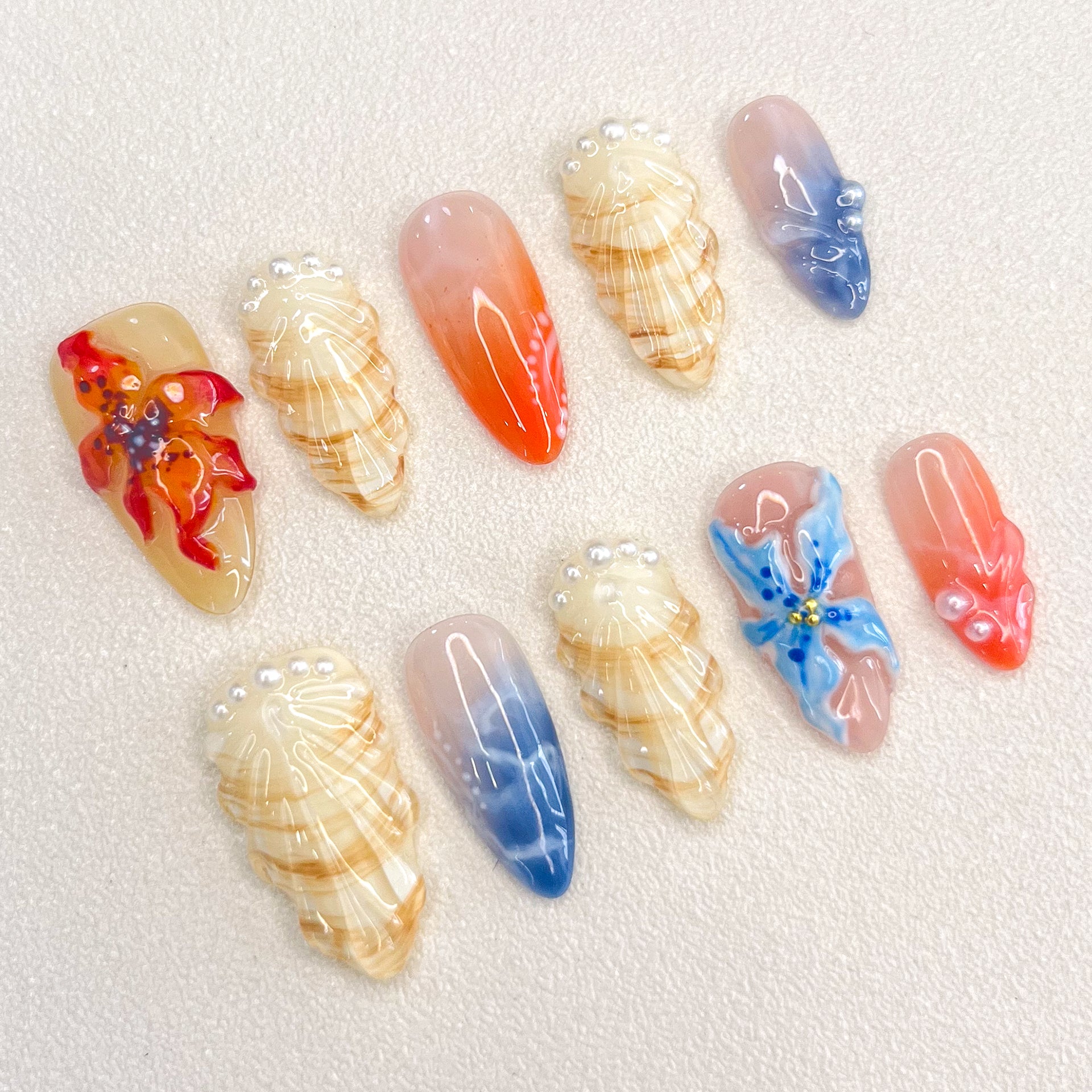 Sunset Coral press-on nails with coral accents, shells, and ocean hues for a beach-inspired, vibrant style.