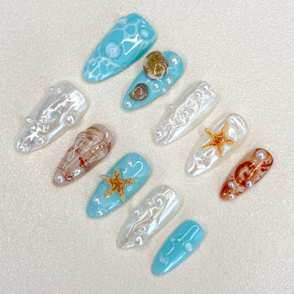 Ocean Pearls press-on nails featuring starfish, shells, and shimmering pearls for a chic, sea-inspired design.