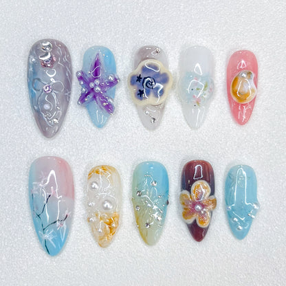 Coastal Whimsy press-on nails with pastel starfish, seashells, and floral accents, creating a serene and elegant coastal vibe.