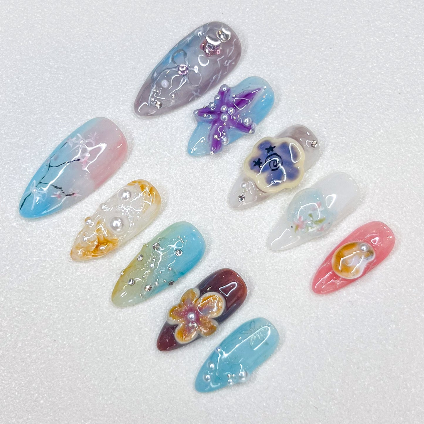 Coastal Whimsy press-on nails with pastel starfish, seashells, and floral accents, creating a serene and elegant coastal vibe.