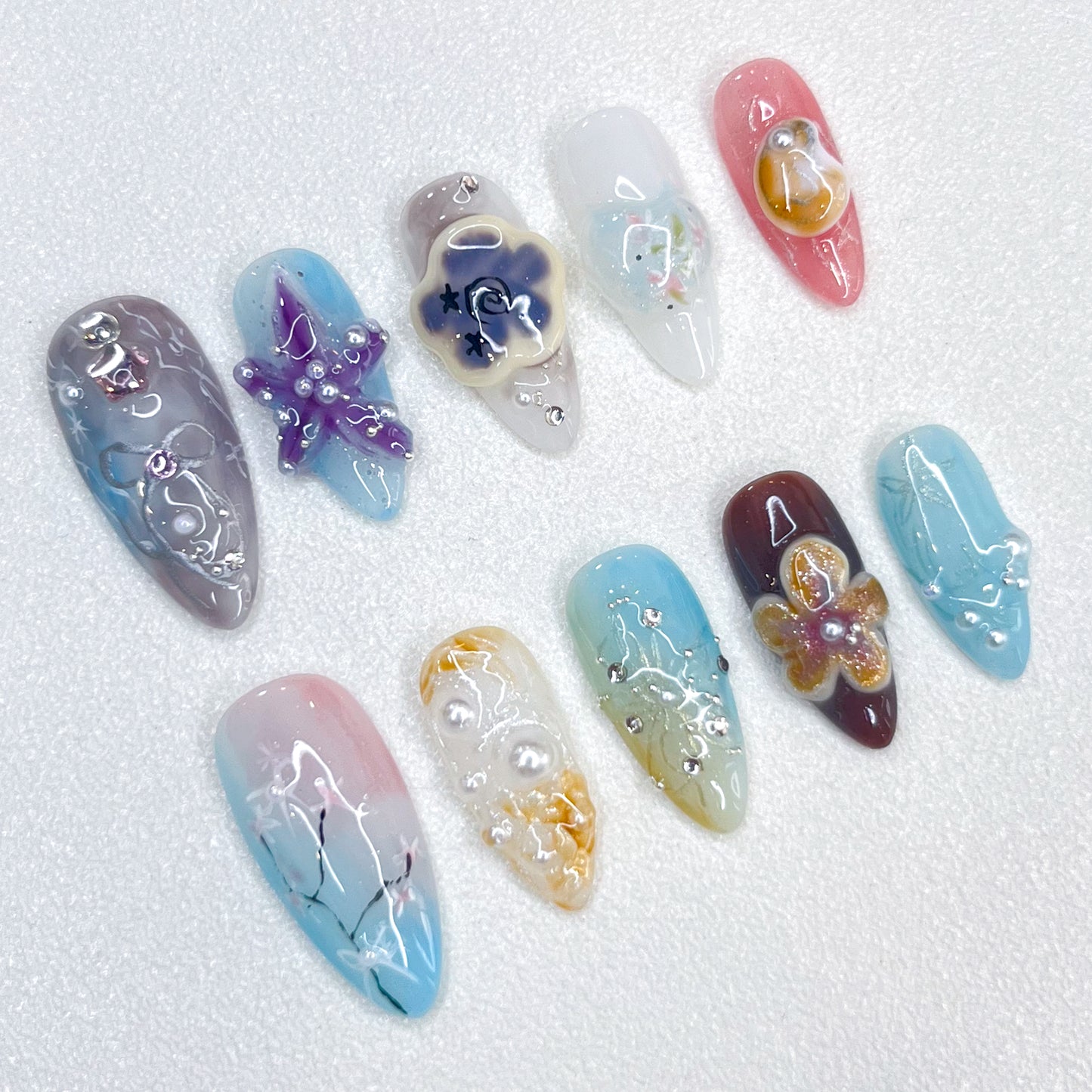 Coastal Whimsy press-on nails with pastel starfish, seashells, and floral accents, creating a serene and elegant coastal vibe.