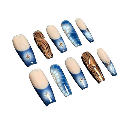 A press-on nail set with gradient blue bases, golden starburst designs, bronze wave patterns, and white floral accents, creating a celestial and elegant aesthetic.