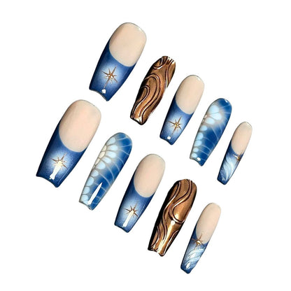 A press-on nail set with gradient blue bases, golden starburst designs, bronze wave patterns, and white floral accents, creating a celestial and elegant aesthetic.