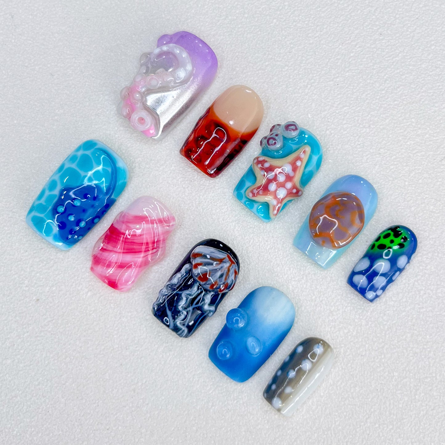 Marine Fantasy press-on nails with jellyfish, starfish, and coral designs in vibrant blues and reds, bringing a touch of marine magic to your nails.