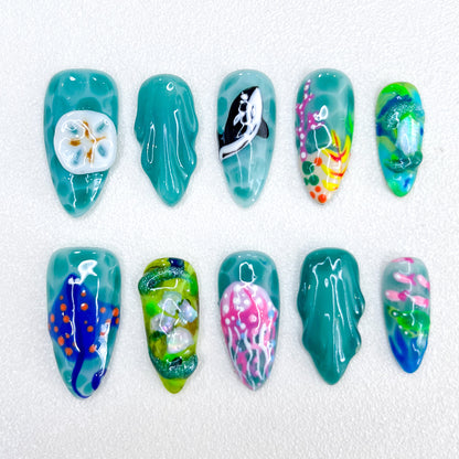 Jellyfish Dreams press-on nails with jellyfish and coral details, paired with vibrant teal tones for a unique oceanic style.