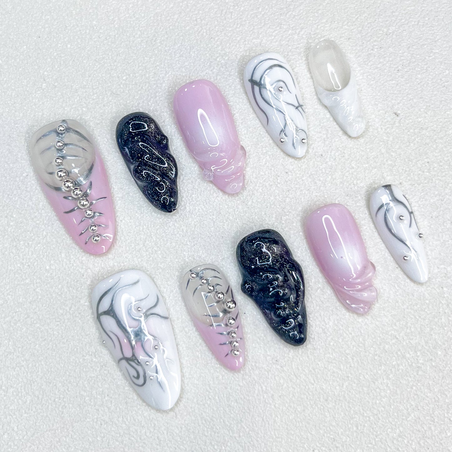 Metallic Symphony press-on nails with abstract patterns, metallic silver accents, and bead details for a striking and modern style.